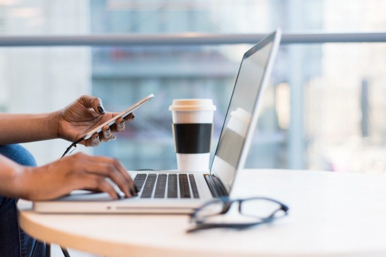 close-up of a hand holding a pen and a laptop